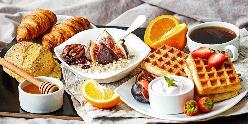 Breakfast with oatmeal, waffles, croissants and fruit in bed.